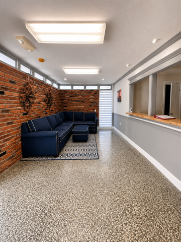 Common lounge inside Rudy's House with sectional sofa and exposed brick wall